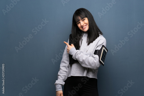 Young sport woman pointing to the side to present a product