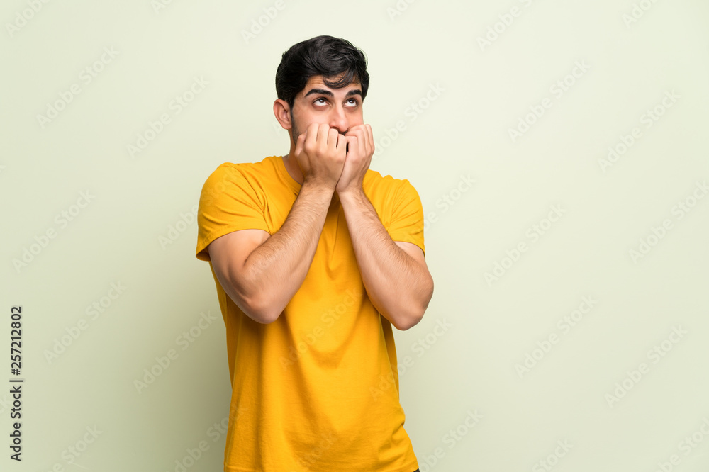 Young man over pink wall is a little bit nervous and scared putting hands to mouth Young man over pink wall is a little bit nervous and scared putting hands to mouth
