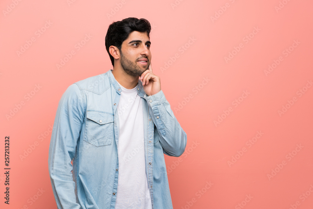 Young man over pink wall thinking an idea while looking up Young man over pink wall thinking an idea while looking up