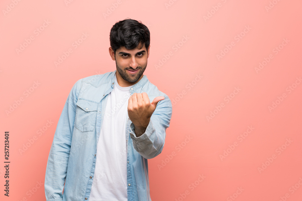 Young man over pink wall inviting to come with hand. Happy that you came Young man over pink wall inviting to come with hand. Happy that you came