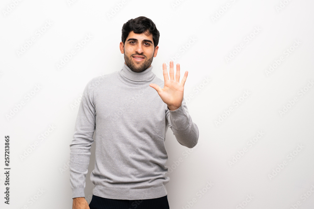 Young man over isolated white wall counting five with fingers Young man over isolated white wall counting five with fingers