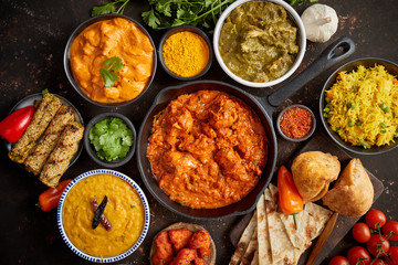 Assortment of various kinds of Indian cousine on dark rusty table