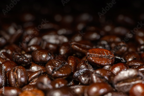 Dark brown roasted coffee beans under artificial light for background © phichak