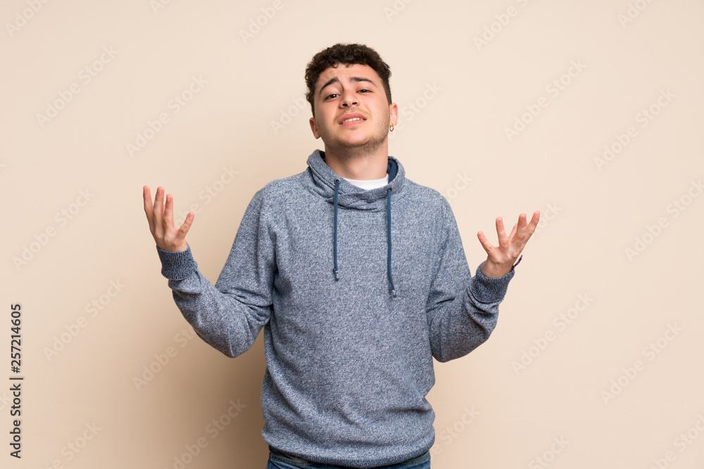 Young man over isolated wall frustrated by a bad situation Young man over isolated wall frustrated by a bad situation
