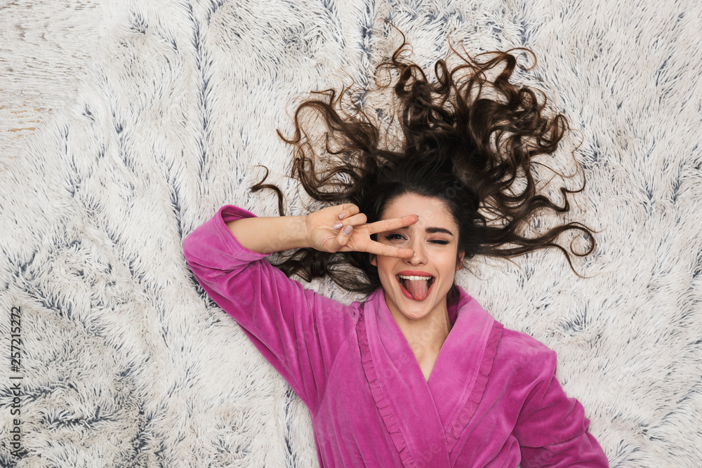 Photo from above of glamour woman wearing girlish housecoat lying on white fur in apartment Photo from above of glamour woman wearing girlish housecoat lying on white fur in apartment