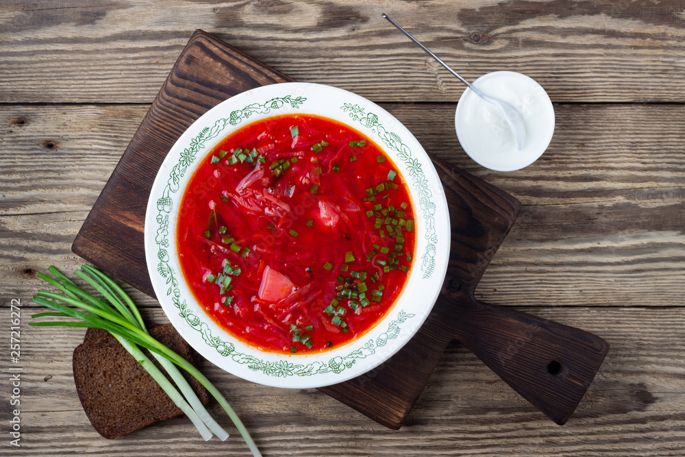 Traditional ukrainian vegetarian beet red soup - borscht with sour cream on wooden background. Top view. Traditional ukrainian vegetarian beet red soup - borscht with sour cream on wooden background. Top view.