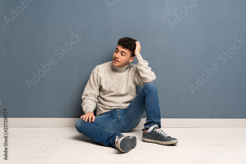 Young man sitting on the floor thinking an idea © luismolinero