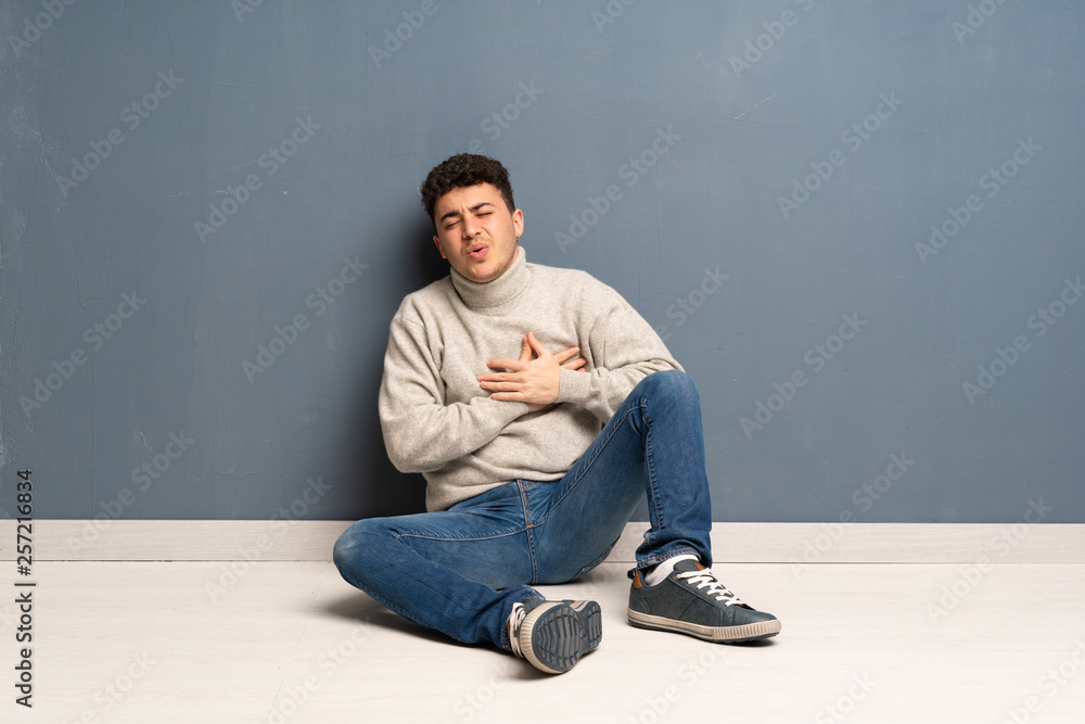 Young man sitting on the floor having a pain in the heart Young man sitting on the floor having a pain in the heart