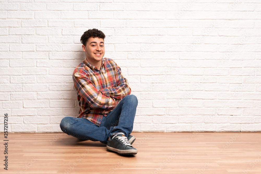 Young man sitting on the floor with arms crossed and looking forward Young man sitting on the floor with arms crossed and looking forward