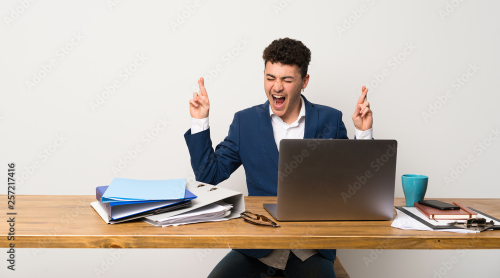Business man in a office with fingers crossing Business man in a office with fingers crossing