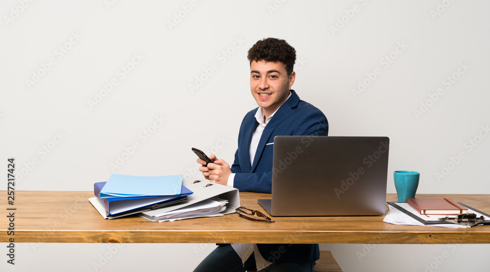 Business man in a office sending a message with the mobile Business man in a office sending a message with the mobile