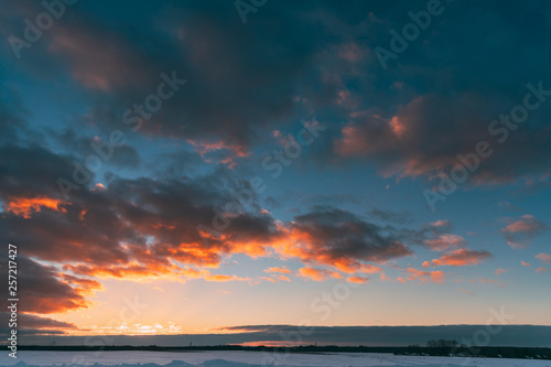 Natural Sunset Sunrise Over Field Or Meadow. Colorful Sky Over Winter Snowy Ground. Landscape Under Scenic Sky At Sunset Dawn Sunrise. Skyline  Horizon