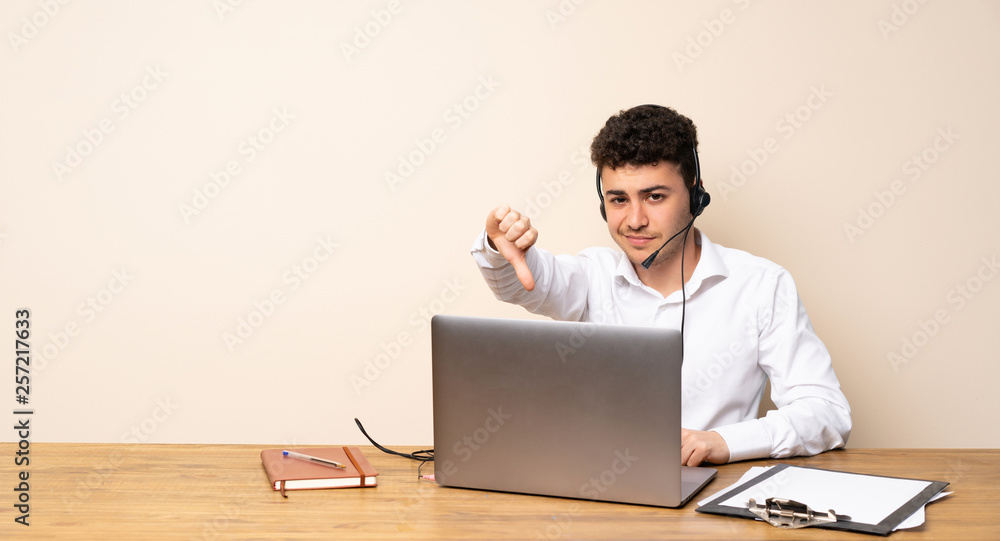 Telemarketer man showing thumb down with negative expression Telemarketer man showing thumb down with negative expression