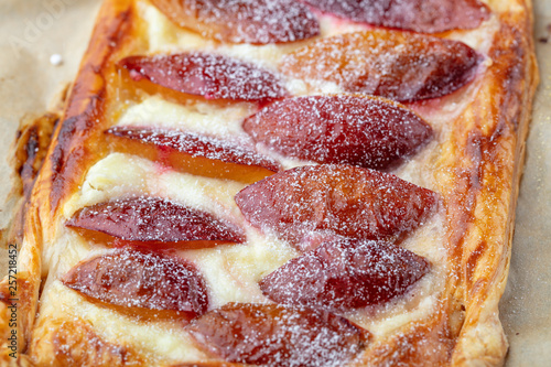 Homemade puff pastry flan with plums, close up. Delicious rectangular galette top view photo