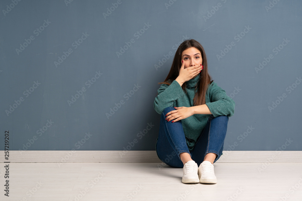 Young woman sitting on the floor covering mouth with hands for saying something inappropriate Young woman sitting on the floor covering mouth with hands for saying something inappropriate