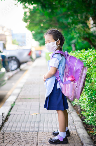 thai girl student with backpack wear a mask against PM 2.5 air pollution before going to school
