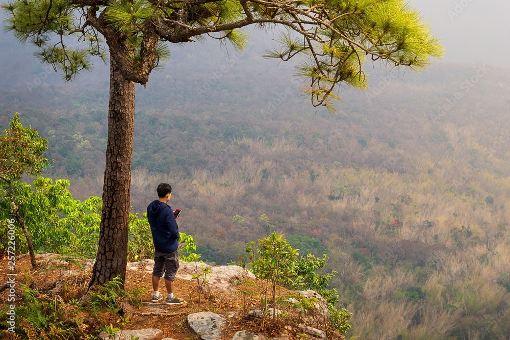 Traveler using mobile on the edge of a cliff nature background