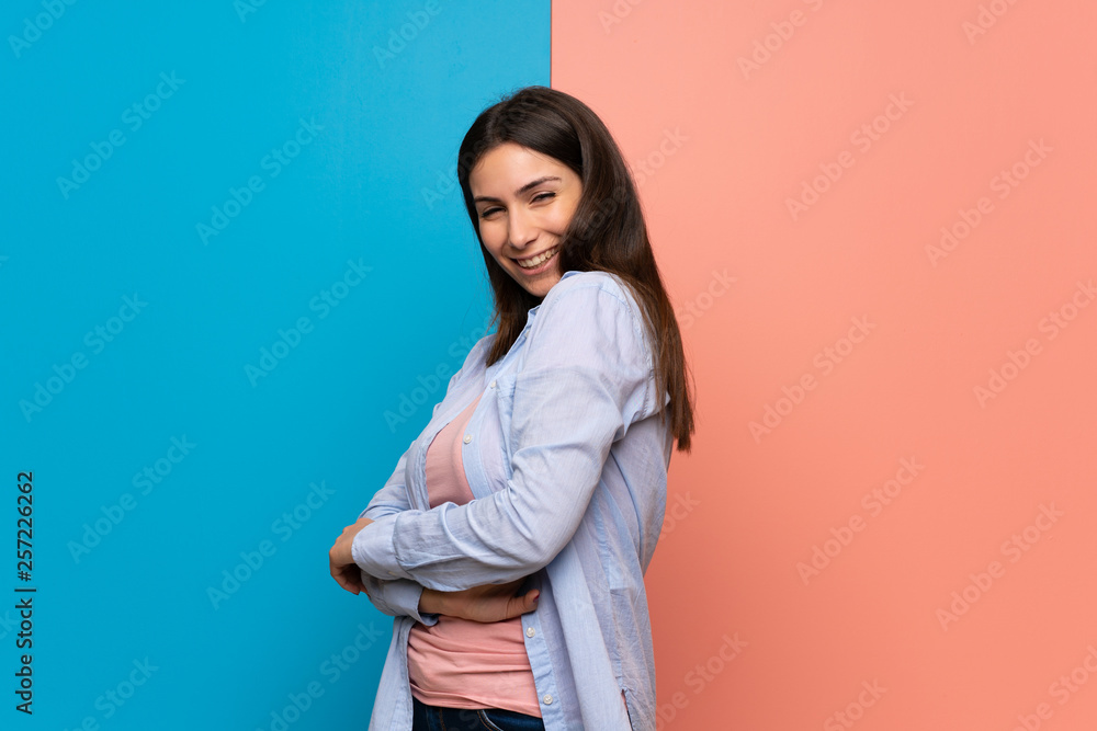 Young woman over pink and blue wall smiling Young woman over pink and blue wall smiling