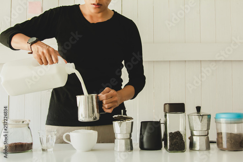 Asian man of Barista is pouring milk latte art in coffee mug. at home in the morning