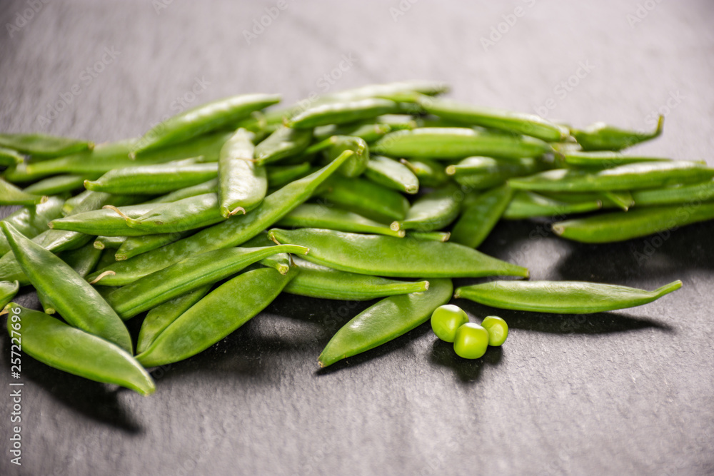 Lot of whole young green sugar snap pea on grey stone Lot of whole young green sugar snap pea on grey stone