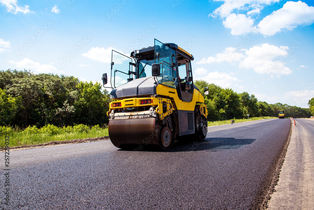 industrial landscape with rollers that rolls a new asphalt in the roadway. Repair, complicated transport movement.