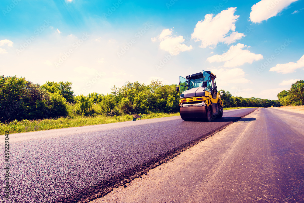 industrial landscape with rollers that rolls a new asphalt in the roadway. Repair, complicated transport movement.