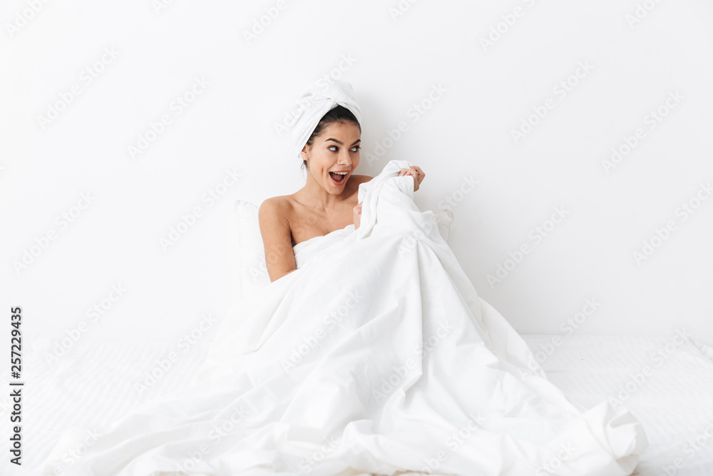 Cheerful young woman sitting in bed after shower Cheerful young woman sitting in bed after shower
