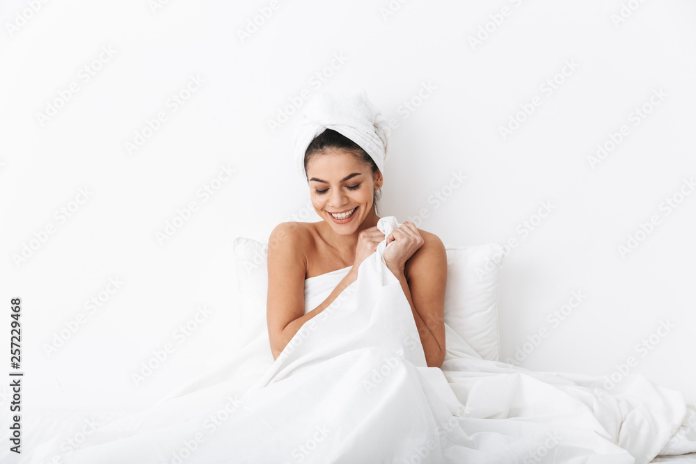 Cheerful young woman sitting in bed after shower Cheerful young woman sitting in bed after shower