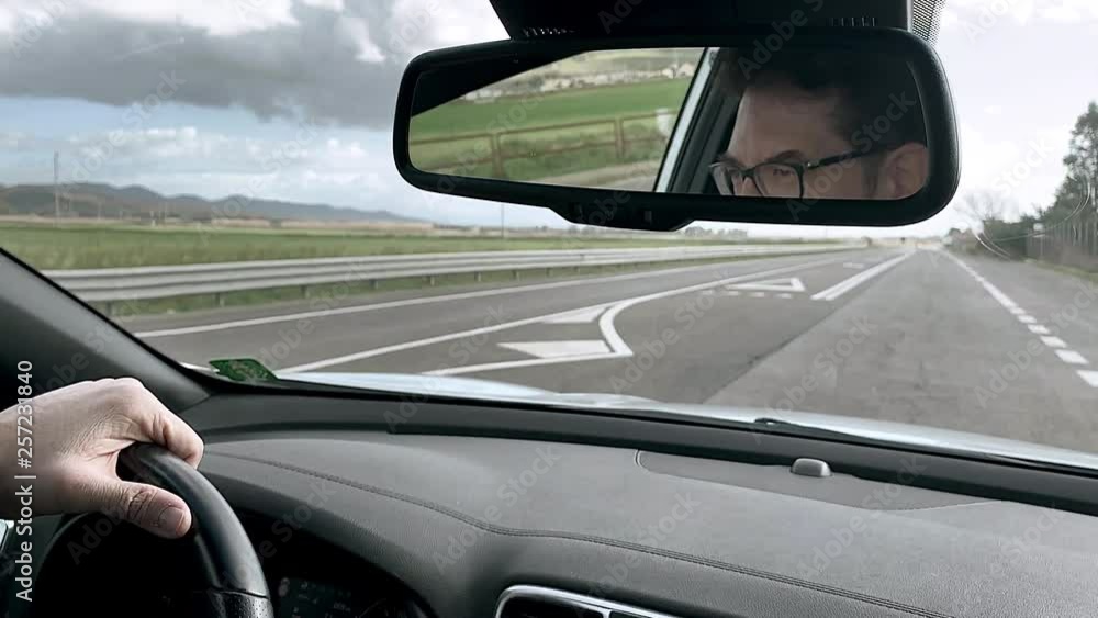Happy handsome man driving car looking himself in mirror adjusting hair Happy handsome man driving car looking himself in mirror adjusting hair