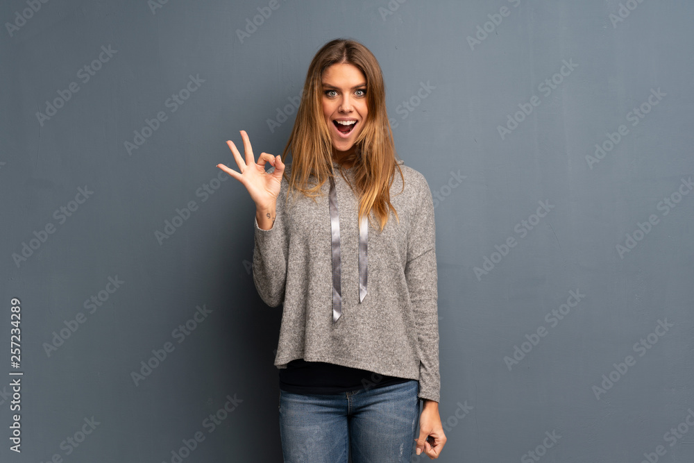 Blonde woman over grey background showing ok sign with fingers Blonde woman over grey background showing ok sign with fingers
