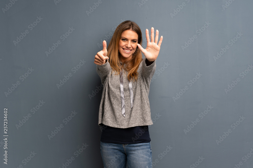 Blonde woman over grey background counting six with fingers