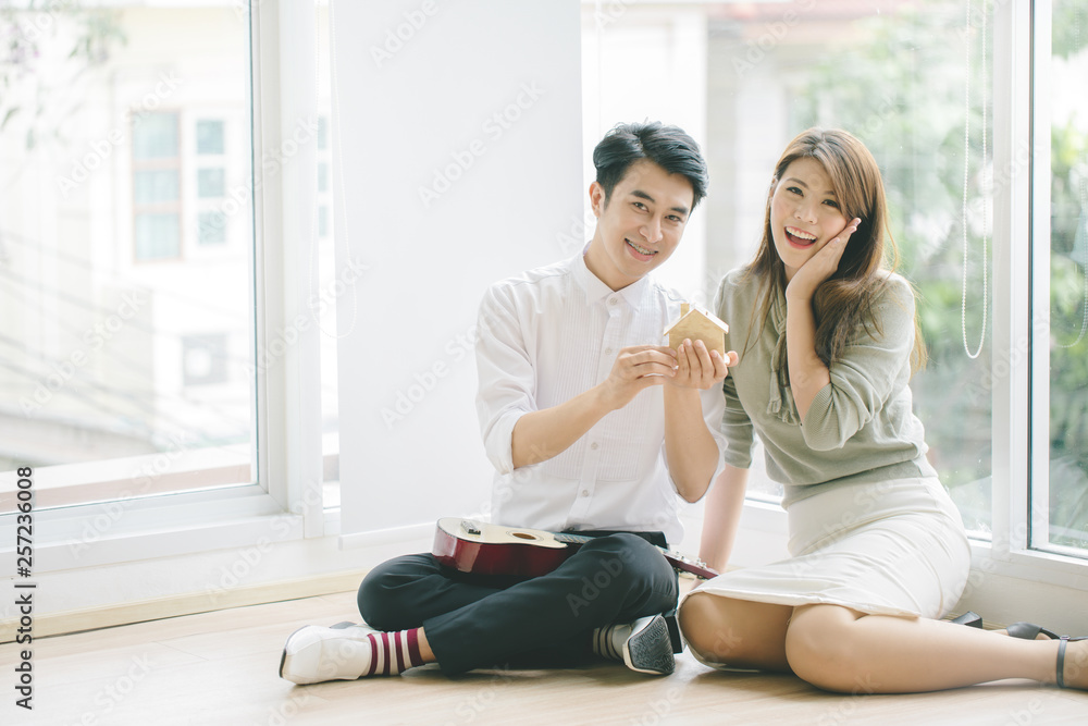 Asian couples plan to buy a house.Hold the model house in hand. Asian couples plan to buy a house.Hold the model house in hand.