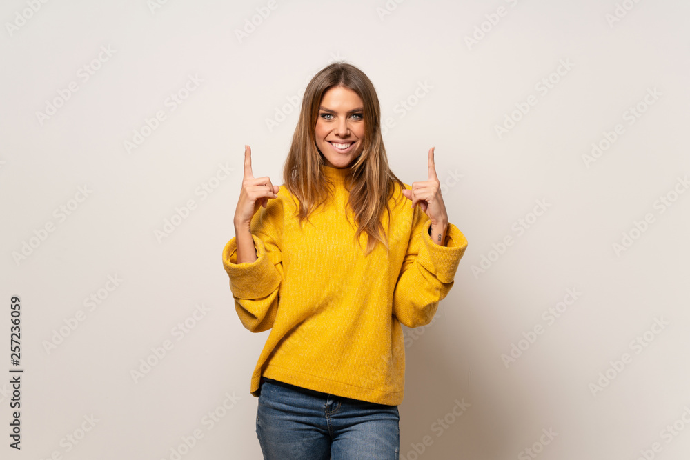 Woman with yellow sweater over isolated wall pointing with the index finger a great idea Woman with yellow sweater over isolated wall pointing with the index finger a great idea