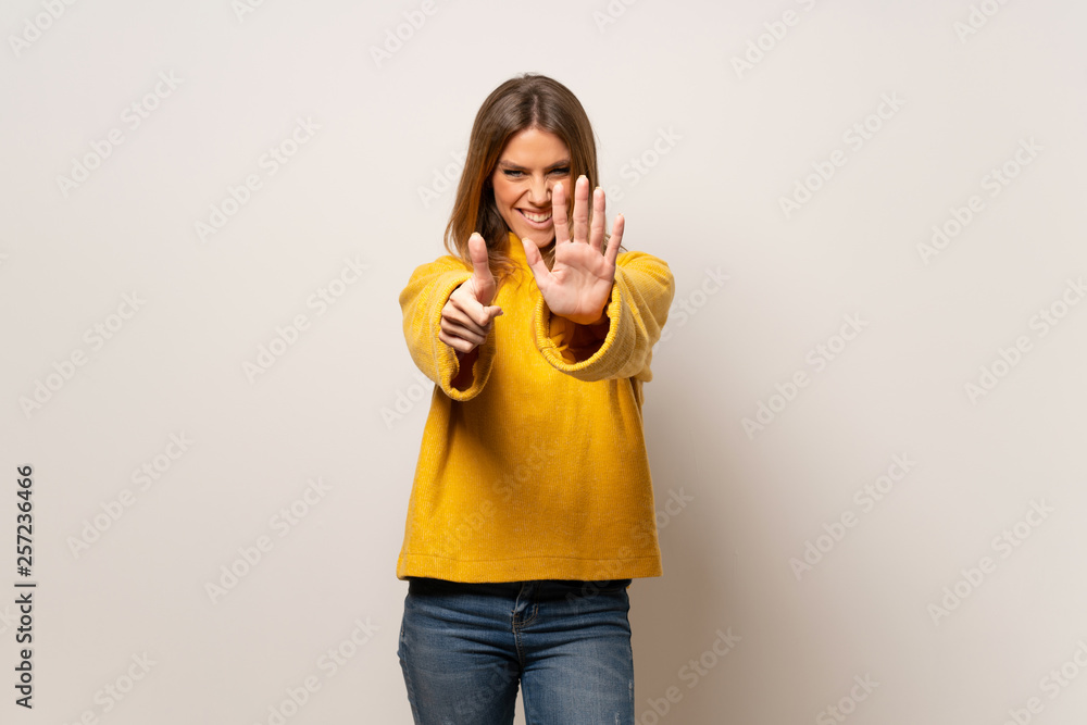 Woman with yellow sweater over isolated wall counting six with fingers Woman with yellow sweater over isolated wall counting six with fingers