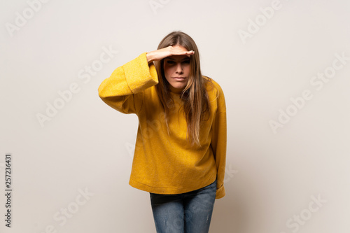 Obraz na plátně Woman with yellow sweater over isolated wall looking far away with hand to look