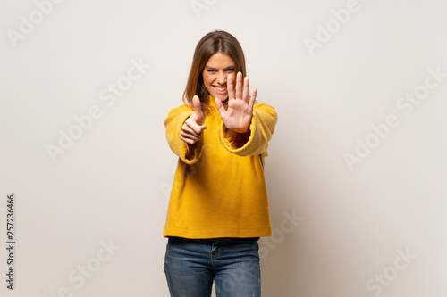 Woman with yellow sweater over isolated wall counting six with fingers