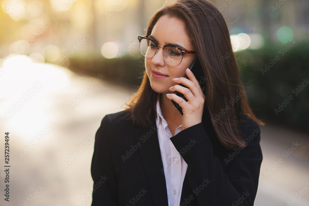 Portrait of beautiful business woman talking with partner via mobile phone while walking on the street Portrait of beautiful business woman talking with partner via mobile phone while walking on the street