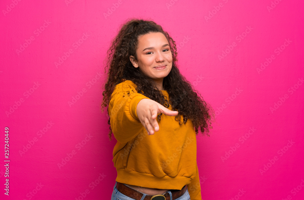Teenager girl over pink wall shaking hands for closing a good deal