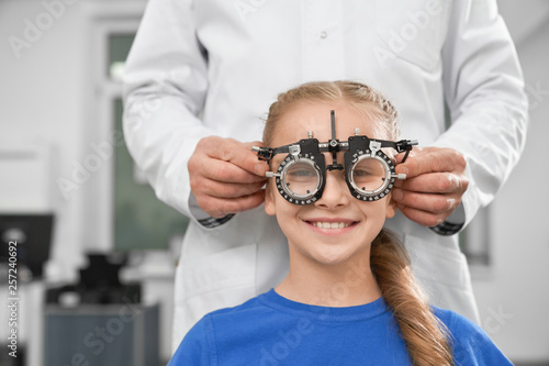 Girl in test glasses, checking eyesight in clinic.