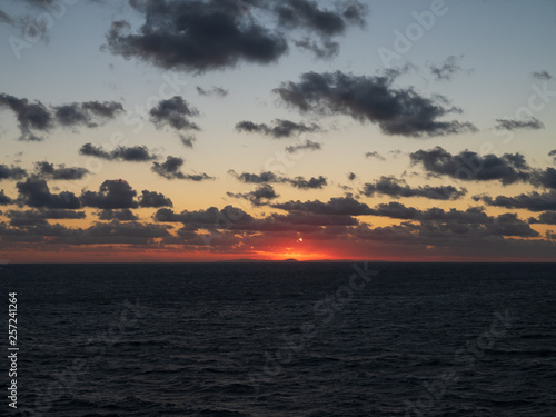 Beautiful orange sky when sunset over the mountain with ocean foreground