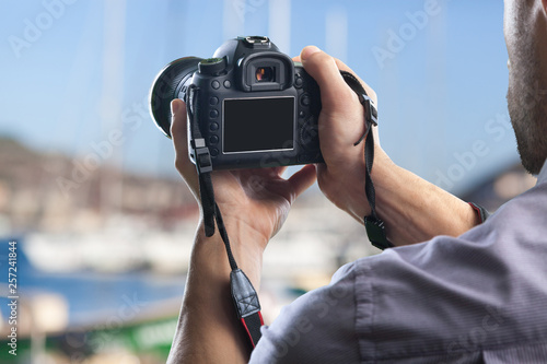 Young man holds modern digital black camera