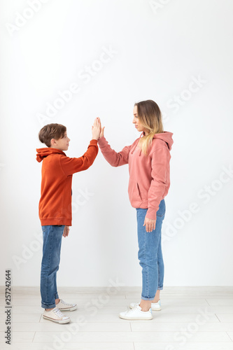 Relationship, mothers day, children and family concept - Mother and son dressed in sweatshirts, high five gesture