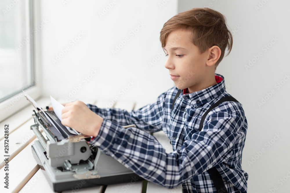 World day of the writer concept - Boy with an old typewriter over window background World day of the writer concept - Boy with an old typewriter over window background