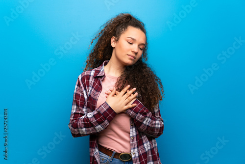 Teenager girl over blue wall having a pain in the heart © luismolinero