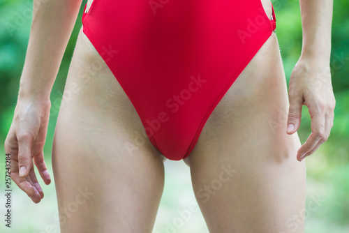Close-up on a slim woman body in a red swimsuite.