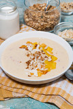 smoothie bowl with mango, coconut and nuts, vertical closeup