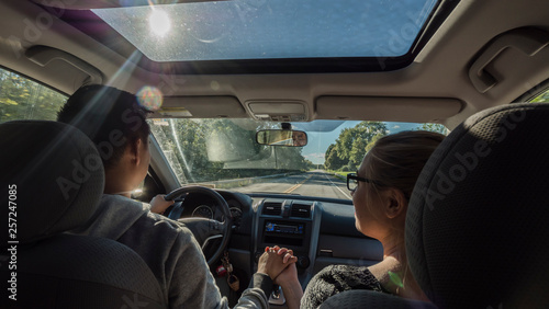 Multi-ethnic couple riding in a car, a man holding a woman's hand © StockMediaProduction