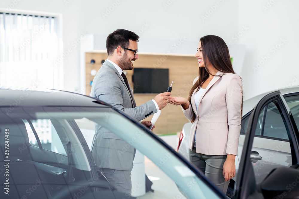 Smiling car salesman handing over your new car keys. Happy girl the buyer. Smiling car salesman handing over your new car keys. Happy girl the buyer.