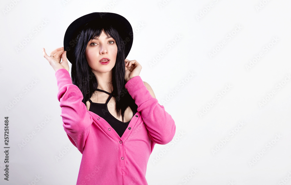Fashionable portrait of smiling elegant brunette girl with red lips in black trendy hat and pink sweater posing over gray wall. Positive mood. Fashionable portrait of smiling elegant brunette girl with red lips in black trendy hat and pink sweater posing over gray wall. Positive mood.