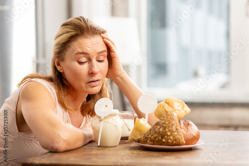 Housewife sitting at the table and looking at foods evoking allergies